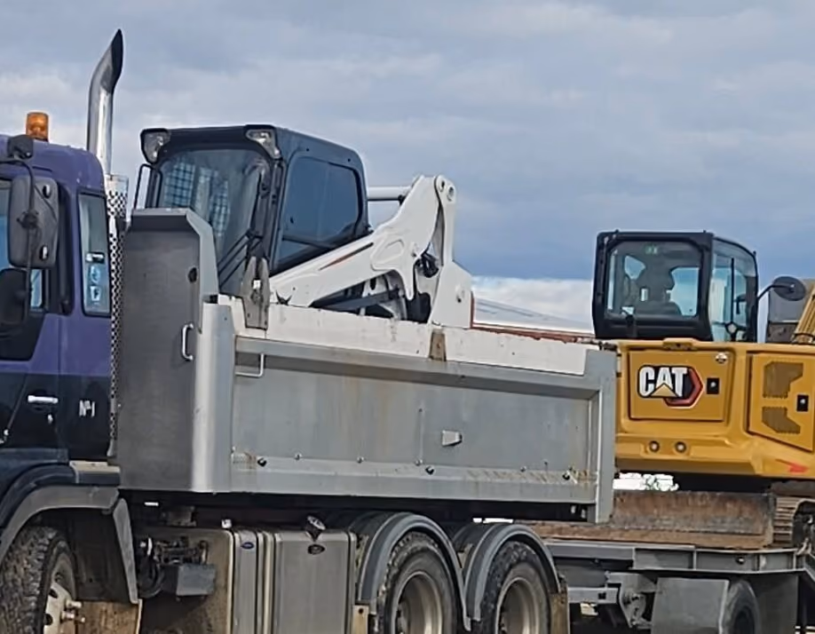 Bobcat skid steer loaded on the tip truck with a Cat digger behind