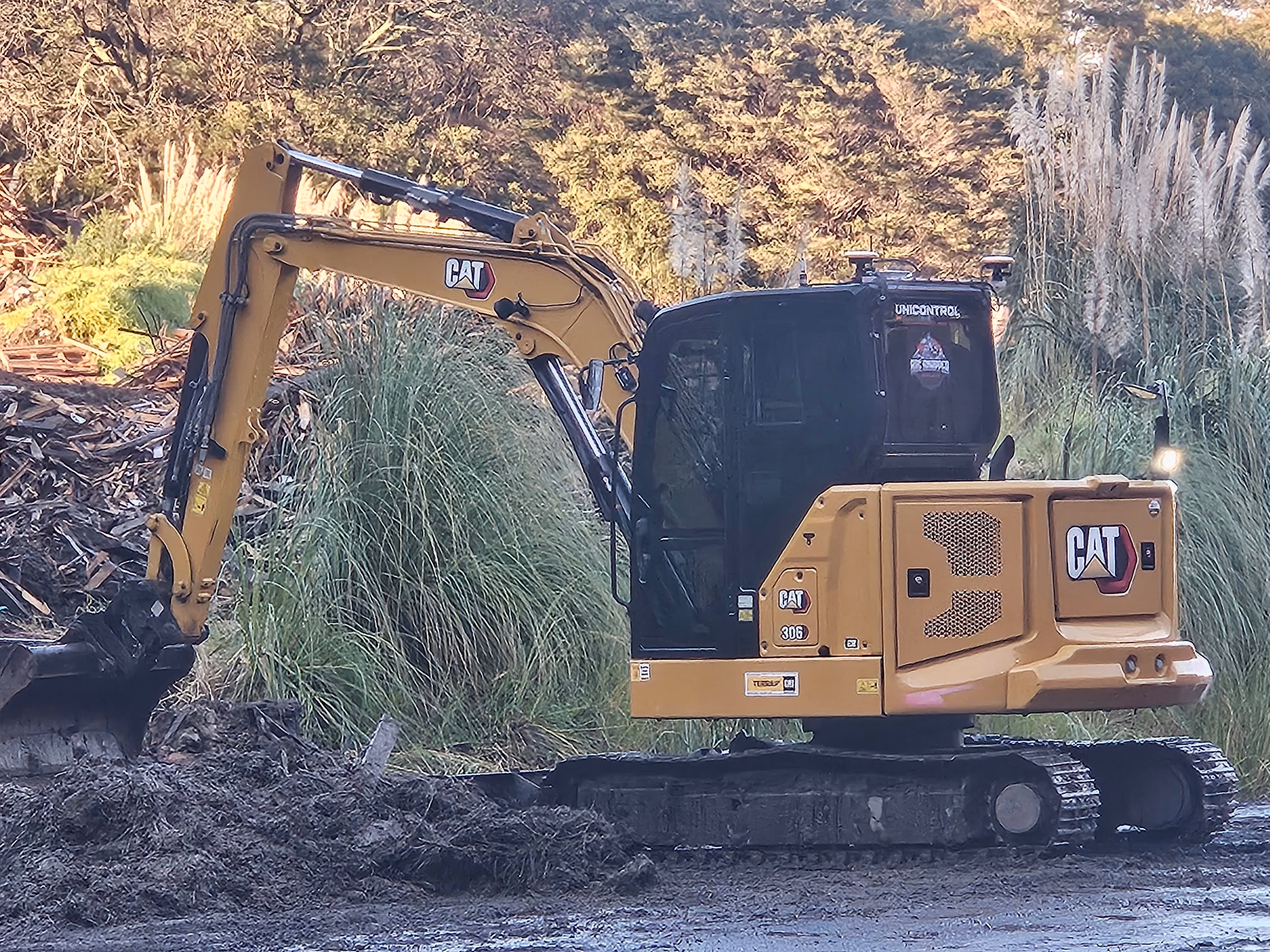 Cat excavator working among the grasses on a wet morning