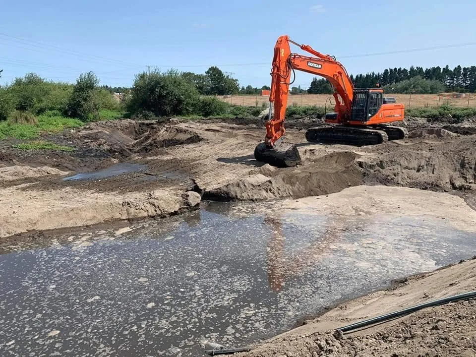 Excavator shaping a pond on a rural Waikato property