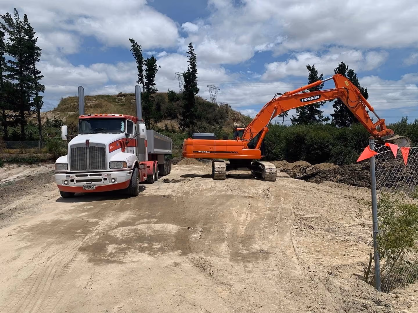 Big Snapper Bobcats truck and trailer beside an excavator on a metal site road